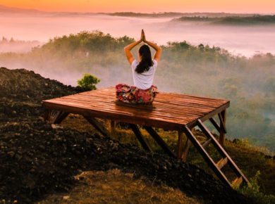 Person relaxing on top of a cloudy valley