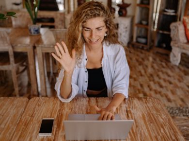 woman speaking and waving hi in front of laptop.