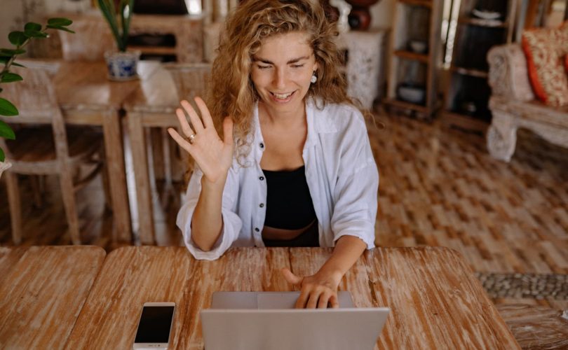 woman speaking and waving hi in front of laptop.