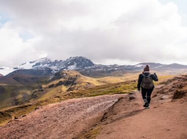 Woman walking with a backpack on a mountain path, symbolizing the invisible burdens and mental load leaders often carry.